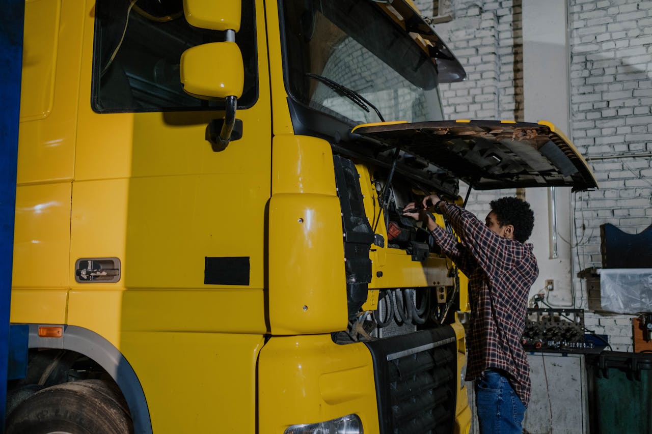 A mechanic working on a truck engine in an indoor mechanical workshop.